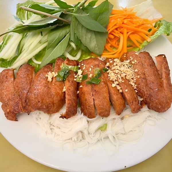 Vietnamese grilled pork sausage (Nem Nuong) with vermicelli noodles, fresh herbs, and shredded carrots.